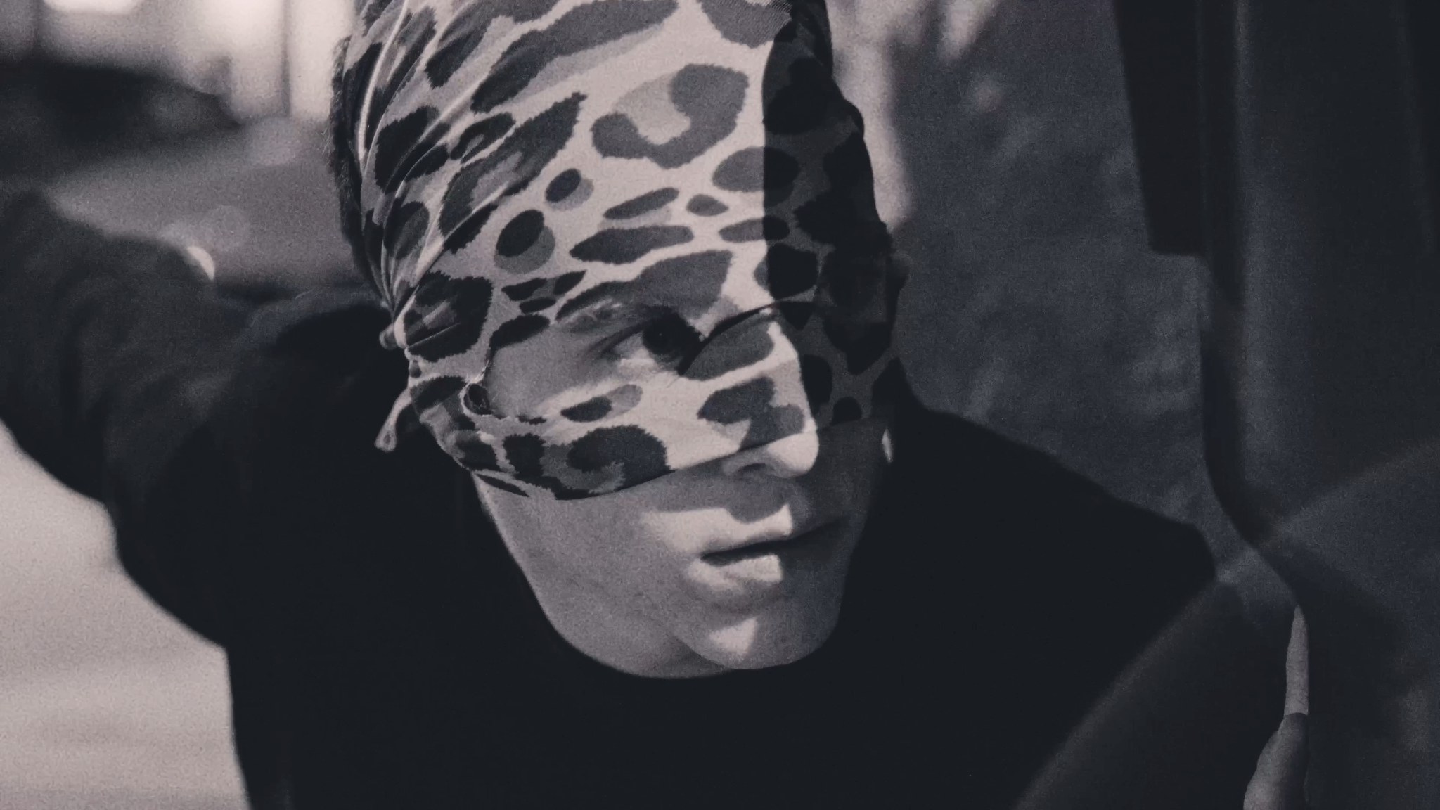 A masked figure wearing a patterned animal-print face covering.
